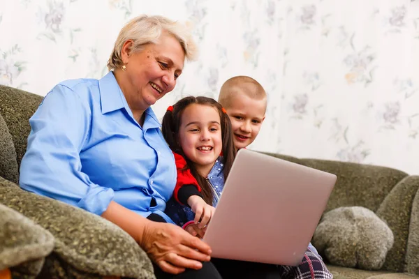 Abuela con nietos usando laptop en casa —  Fotos de Stock
