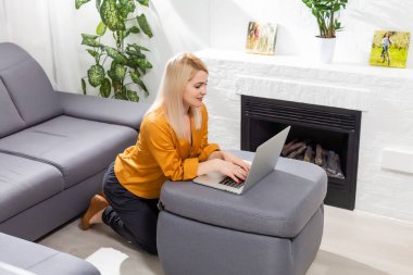 Mutlu, sıradan, güzel bir kadın dizüstü bilgisayarla evde oturuyor..