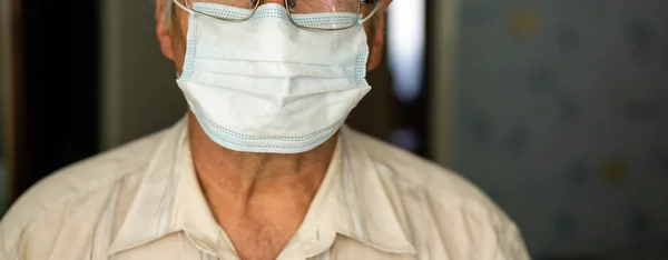 Portrait of an old man in a medical mask. A concept of the danger of coronavirus for the elderly.