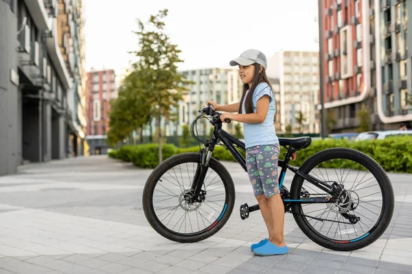 Niña feliz montando una bicicleta en la ciudad — Foto de Stock