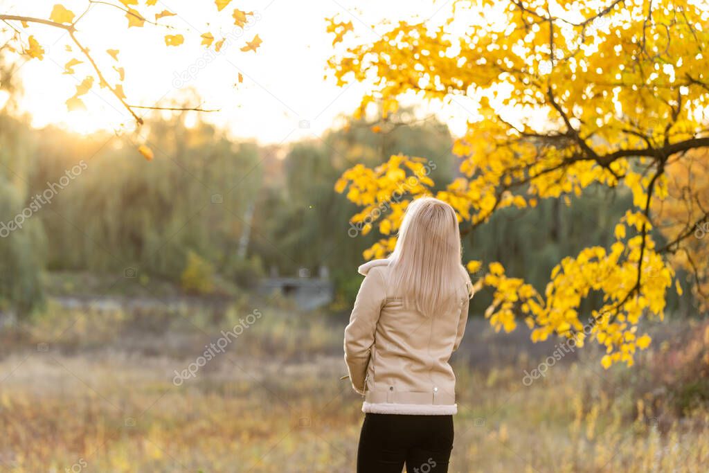 Young woman with clasped hands, praying prayer, standing in nature in autumn