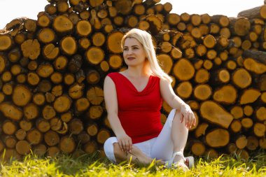 Parkta çimlerin üzerinde ağaçta oturan kadın.