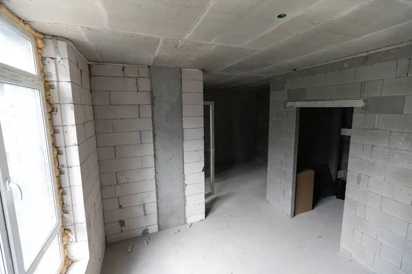 Pequeno apartamento sem reparo em um novo edifício. Um quarto numa casa inacabada. Paredes de bloco de espuma e piso de concreto em um apartamento minúsculo. — Fotografia de Stock