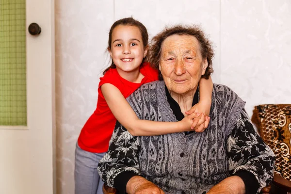 Senioren vrouw knuffelen kleindochter terwijl zitten op bank thuis — Stockfoto