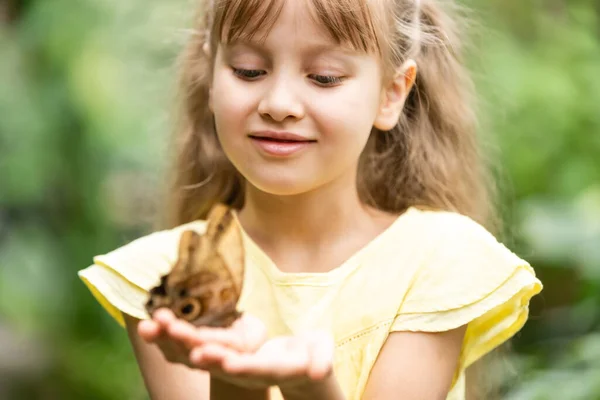 Menina segurando borboleta em sua mão. — Fotografia de Stock