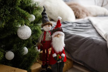 Noel kış tatili konsepti. Süslü Noel ağacı, kırmızı yastıklı rahat kanepe, duvarda saatler.