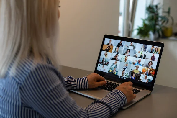 Back view of business woman talking to her colleagues about plan in video conference. Multiethnic business team using laptop for a online meeting in video call. Group of people smart working from home — Stock Photo, Image