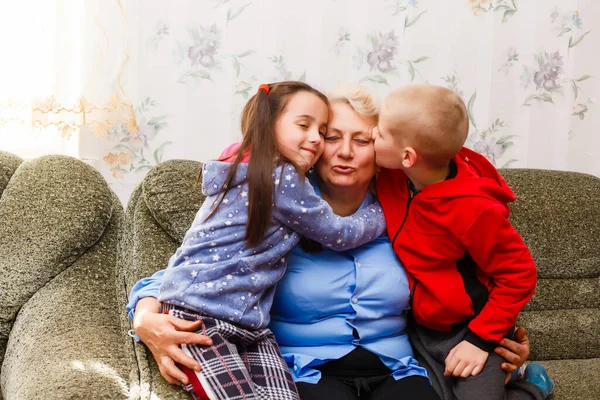 Grandmother and grandchildren sitting together on sofa in living room — Stock Photo, Image