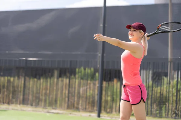 Femme jouant au tennis tenant une raquette et souriant — Photo