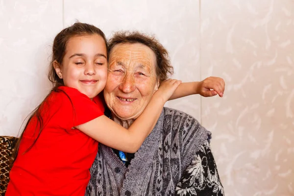 Conceito de ligação familiar. Linda menina feliz emracing sua avó na sala de estar leve — Fotografia de Stock