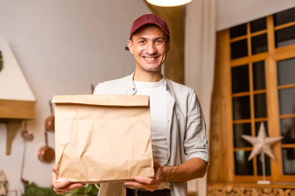 Young delivery man holding and carrying a cardbox. Buy food online in quarantine concept.