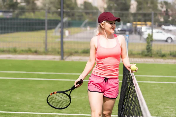 Kvinna som spelar tennis håller ett oväsen och ler — Stockfoto