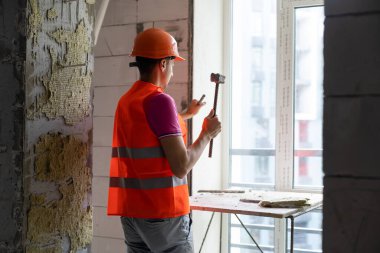 Elinde çekiç ve keski tutan genç bir işçi.