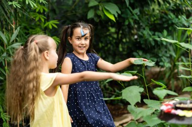 Serada kelebekleri olan iki küçük kız