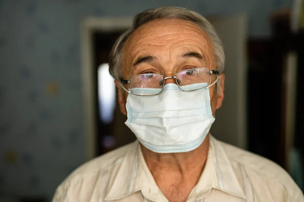 Portrait of an old man in a medical mask. A concept of the danger of coronavirus for the elderly.