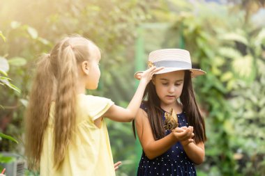 İki kız kardeş ellerinde bir kelebek tutuyor. Doğayı keşfeden çocuklar. Yazın çocuklarla aile eğlencesi..