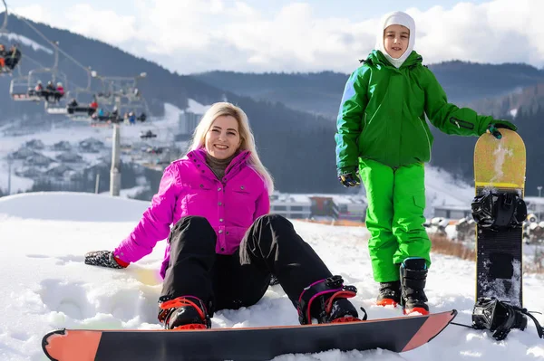 Mãe e filha com snowboards em um resort de montanha — Fotografia de Stock