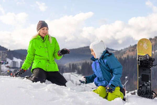 Moeder en dochter met snowboards in wintersportplaats — Stockfoto