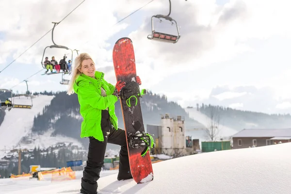 Jeune femme tenant snowboard à la station d'hiver — Photo