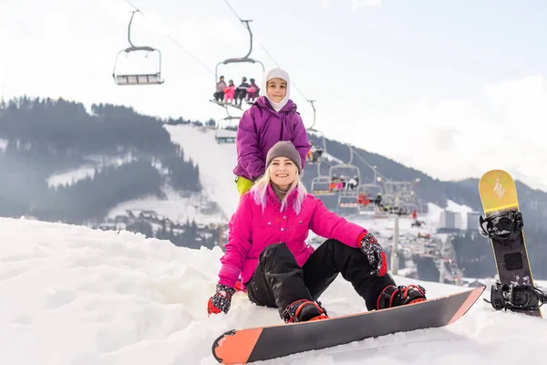 在冬季度假胜地有雪板的年轻母亲和女儿 — 图库照片