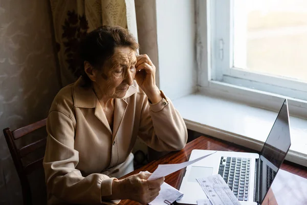 Emeryt czyta niezliczone gazety i jest bardzo skupiony. Starsza kobieta obliczająca podatki w domu. Emerytka obliczająca swoje rachunki. Koncepcja działalności gospodarczej, oszczędności, ubezpieczenia emerytalnego, wieku i osób — Zdjęcie stockowe