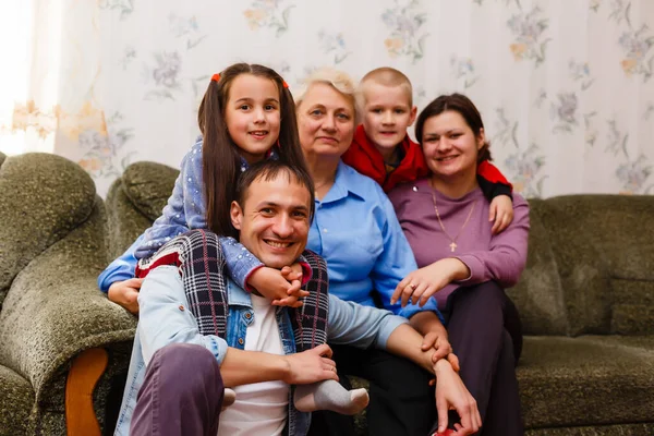 Grootmoeder en kleinkinderen zitten samen op de bank in de woonkamer — Stockfoto