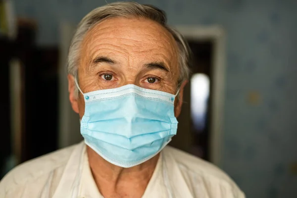 Portrait of an old man in a medical mask. A concept of the danger of coronavirus for the elderly.