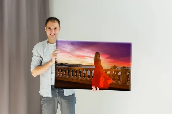Mężczyzna trzyma zdjęcie płótno w domu — Zdjęcie stockowe