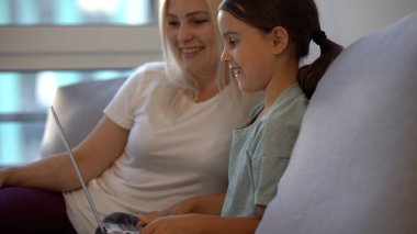 Küçük kız ödevini evde yapıyor ve dizüstü bilgisayar kullanıyor.