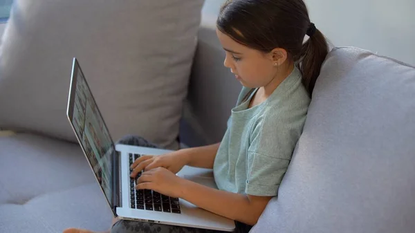 Ragazzina carina che usa il portatile a casa. Istruzione, studio online, studio a casa, apprendimento a distanza, scolaretta concetto di stile di vita dei bambini — Foto Stock