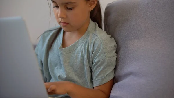 Bambina che fa i compiti a casa e utilizza un computer portatile — Foto Stock