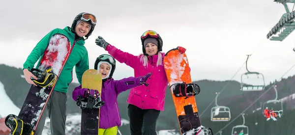 Porträt einer glücklichen Familie mit Snowboards vor blauem Hintergrund — Stockfoto