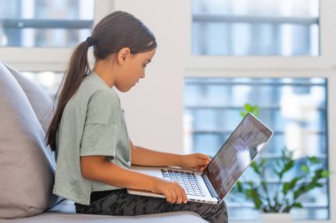 Evde dizüstü bilgisayar kullanan tatlı bir kız. Eğitim, çevrimiçi öğrenim, ev eğitimi, uzaklık öğrenimi, liseli çocukların yaşam tarzı konsepti