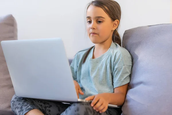 Ragazzina carina che usa il portatile a casa. Istruzione, studio online, studio a casa, apprendimento a distanza, scolaretta concetto di stile di vita dei bambini — Foto Stock