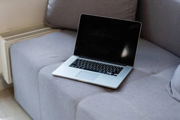 Närbild av stängd laptop ligger på grå soffa — Stockfoto