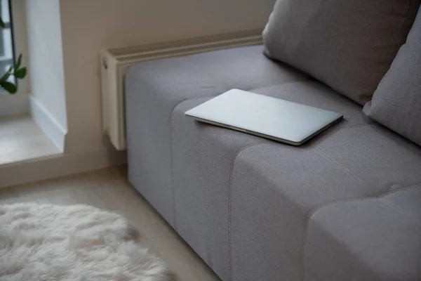 회색 소파에 누워 있는 폐쇄형 노트북의 확대 사진 — 스톡 사진