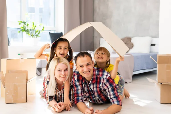Gelukkige familie verhuizen naar huis met dozen rond — Stockfoto