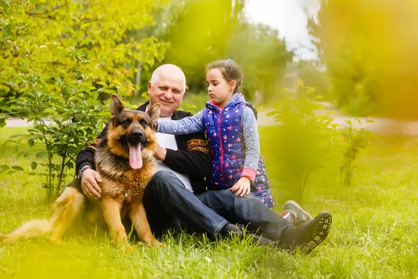 Dziadek z wnuczką i psem w ogrodzie — Zdjęcie stockowe