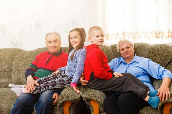 Gelukkig jong jongen en meisje met hun lachen grootouders glimlachen naar de camera als ze samen poseren binnen — Stockfoto