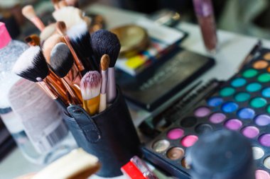 Profesyonel makyaj fırçaları tüpte. Göz farı paleti ve bir şişe mikiler suyu. Güzellik salonu