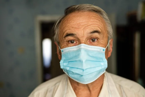 Коронавірус карантин. Старший чоловік, одягнений в захисну маску за вікном, залишається вдома, щоб уникнути зараження COVID-19 - концепція відповідальності і запобігання. — стокове фото