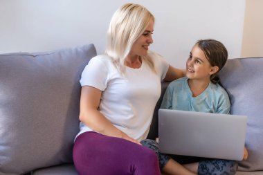 Anne ve kızı birlikte dizüstü bilgisayara bakıyorlar.