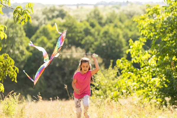 Kleines Mädchen läuft mit einem Drachen im Freien — Stockfoto