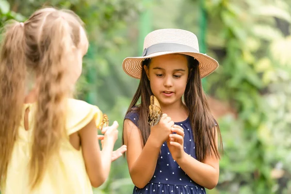 Дві маленькі дівчата з метеликами в теплиці — стокове фото