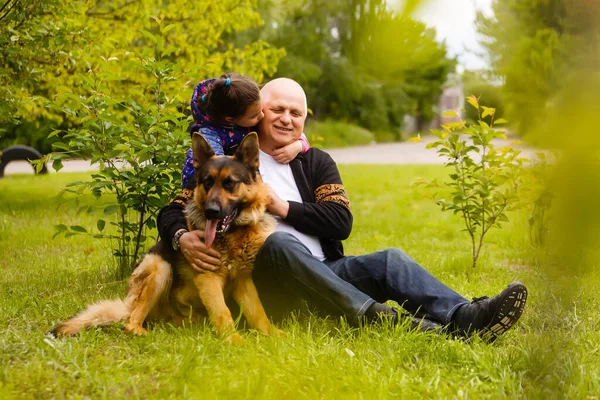 Grand-père avec sa petite-fille et un chien dans le jardin — Photo