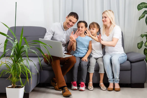 Молода радісна випадкова сім'я з двома дітьми і пара сидить на дивані і дивиться смішне відео або мультфільми в тачпад — стокове фото