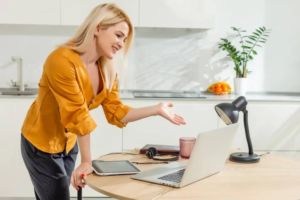 Mooie blanke vrouw die aan laptop werkt. Keuken achtergrond. — Stockfoto