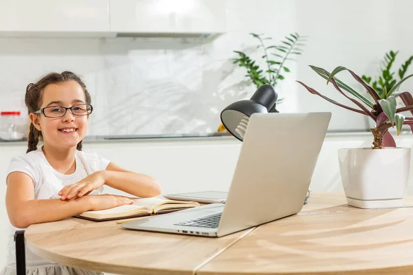 Foto van positieve kid meisje studie remote zitten bureau tafel gebruik laptop hebben online communicatie les met tutor schrijven verslag in huis binnen — Stockfoto