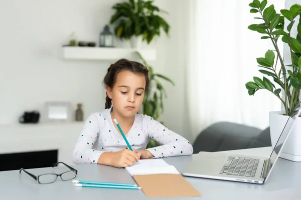 Klein meisje studeren online met behulp van haar laptop thuis — Stockfoto