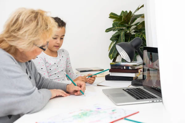 Şirin ve mutlu küçük kız büyükannesiyle dizüstü bilgisayar kullanıyor, online e-öğrenim sistemi üzerinden çalışıyor.. — Stok fotoğraf